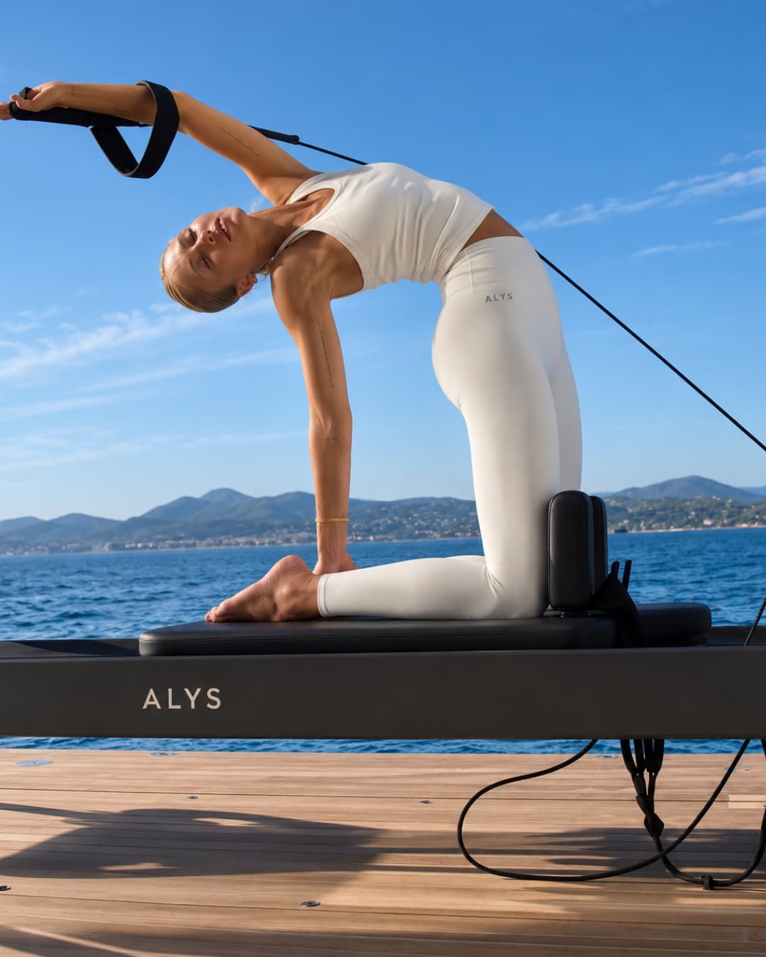 Pilates reformer on yacht deck, Riviera backdrop
